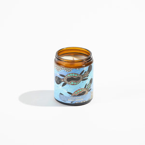 Candle in brown jar with platypus aboriginal design on the label.