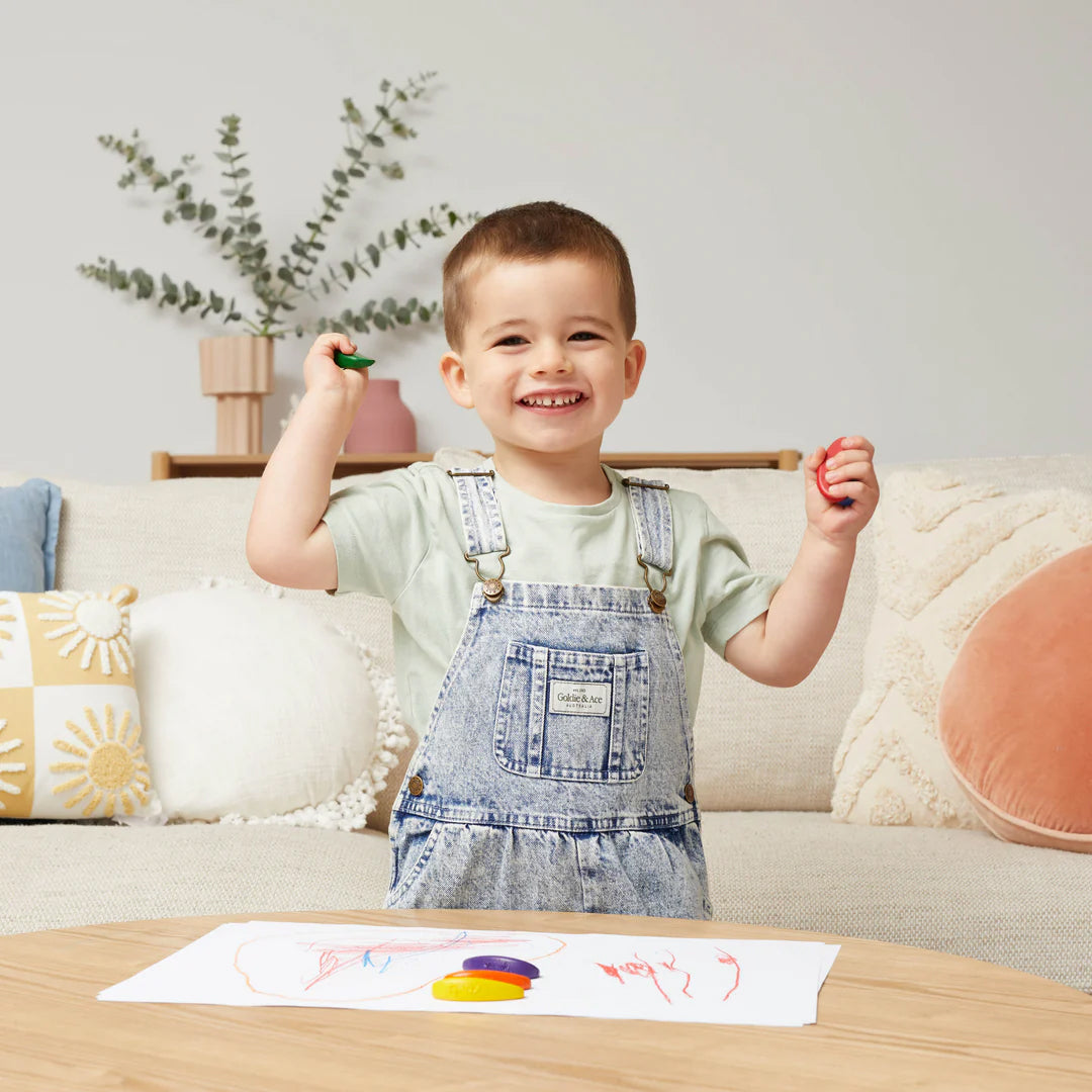 Image of child standing at coffee table with drawing and crayons on coffee table