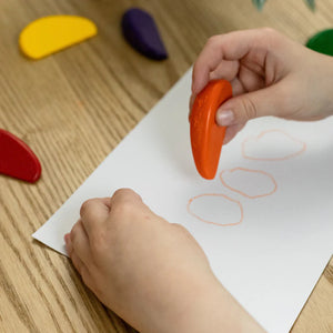 Image of child's hands holding eco crayon above drawing paper