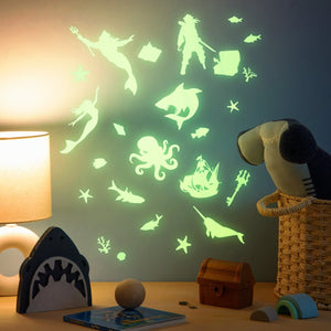 Glow decals on a wall with a wood desk with children toys and a lamp.