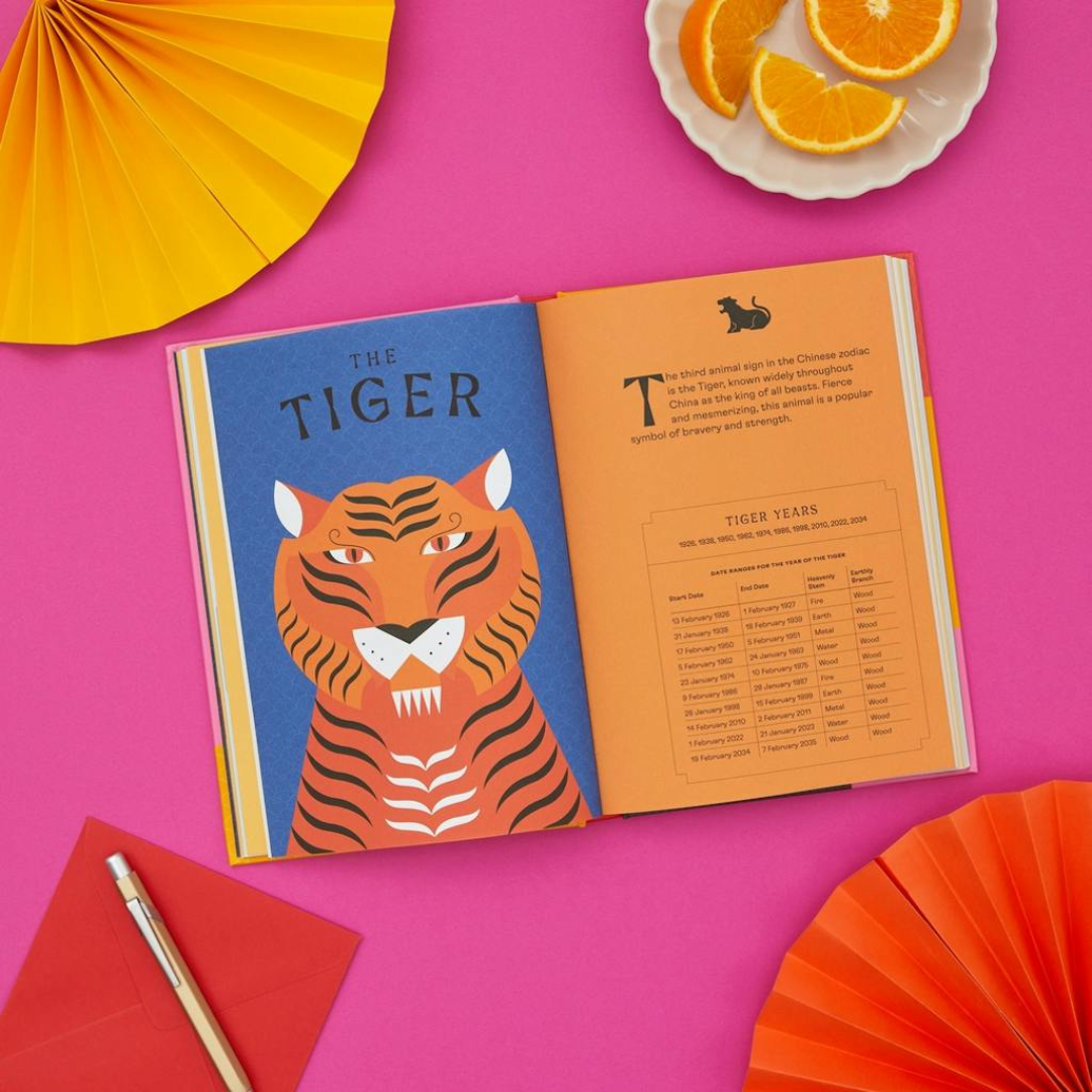 Image of book titled Chinese Astrology: Decode the Zodiac to Live Your Best Life showing open book on pick surface with illustration of tiger on blue background.  