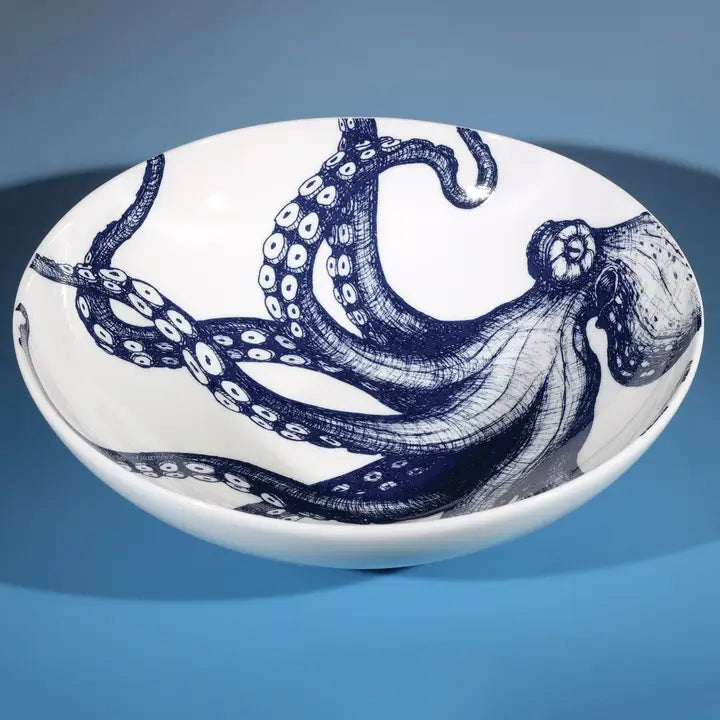 White ceramic bowl with intricate blue octopus illustration, styled on a blue background for coastal-themed kitchen decor.