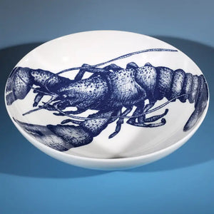 White ceramic bowl with intricate blue lobster illustration inside, styled on a blue background for coastal-themed decor.