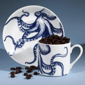 White espresso cup and saucer with blue octopus design, filled with coffee beans, styled on a blue background.