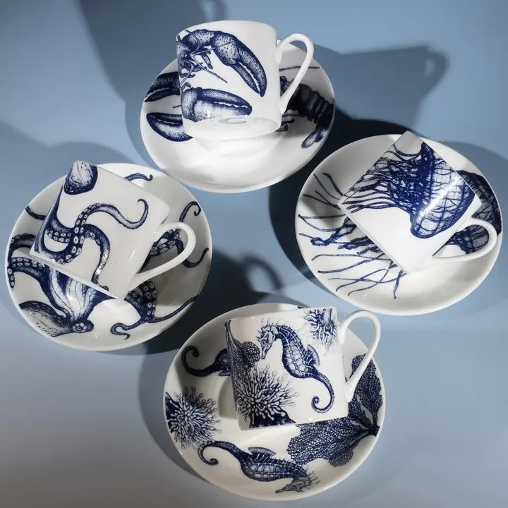 Set of four white espresso cups and saucers with blue marine life designs—octopus, seahorse, lobster, jellyfish.