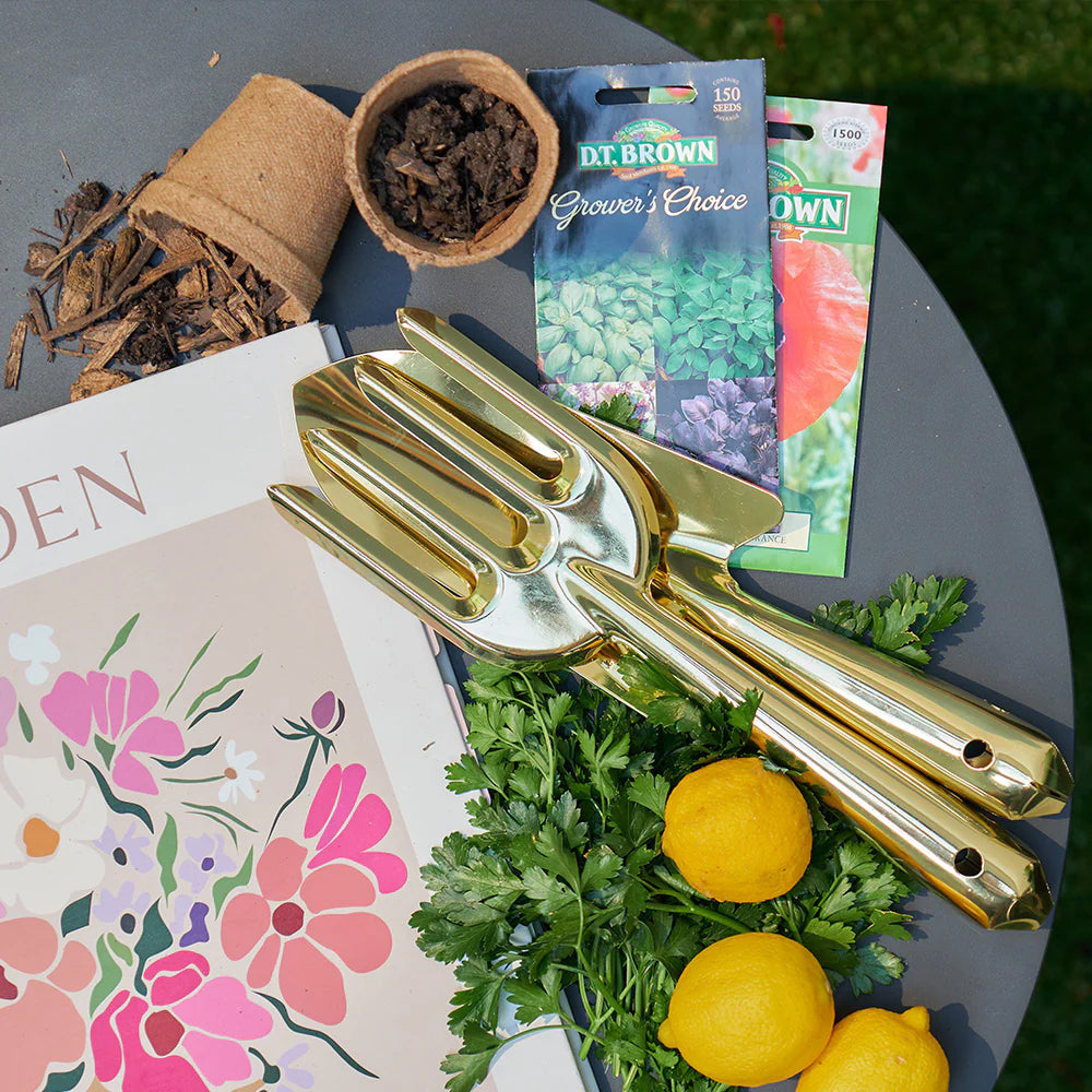 Image of gold garden tools laying on outdoor tale surrounded by various garden items