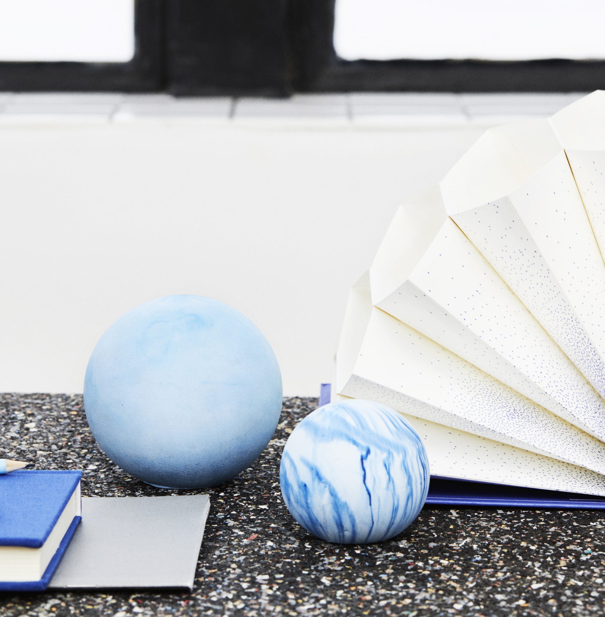 Two marbled blue spheres on a speckled surface, with two closed books and a fanned open book in the background.