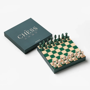 Chess set with green and beige board, pieces in starting positions—dark green vs. light beige. A matching dark green box labeled 'CHESS' sits beside the board.