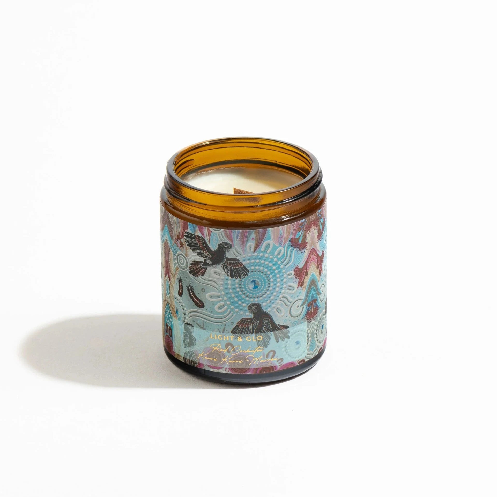 Candle in brown glass jar with blue floral label  with black cockatoos