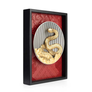 Image of 2025 Year of the Snake Plaque by Royal Selangor, showing gold snake on a silver circle with red textured background and black frame, on white background.