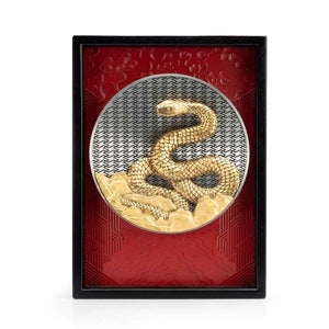 Image of 2025 Year of the Snake Plaque by Royal Selangor, showing gold snake on a silver circle with red textured background and black frame, on white background.