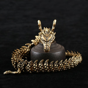 "Golden dragon figurine with intricate scales and horns, coiled around a dark cylindrical object. The dragon’s head faces forward against a black background."