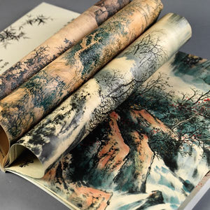 Image of Gift and Creative Papers Book – Chinese Art Edition, showing open book with Chinese landscape artworks and curled pages.