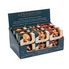 Image of display box of Lost & Found wooden puzzles inspired by ancient civilizations, featuring a variety of intricately shaped brain teasers in individual packaging, neatly arranged in a dark teal and gold-themed cardboard display stand.