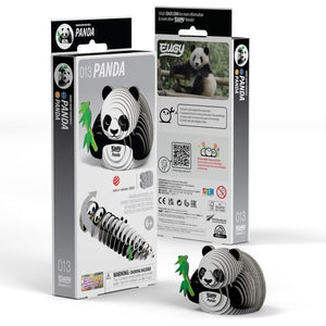 Image of black and white 3D Eugy panda model made of layered, recyclable cardboard, sitting upright and holding a green stick of bamboo, and packaging, against a white background.