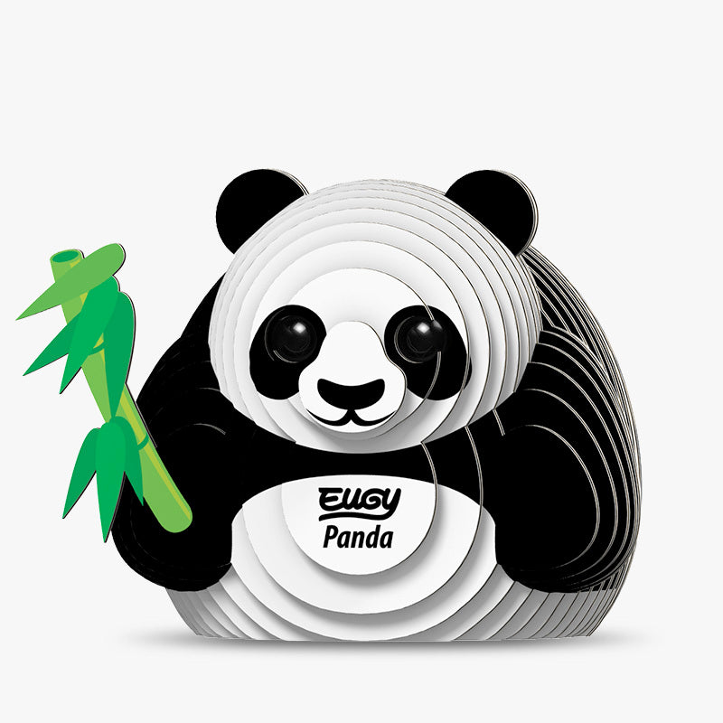 Front view image of black and white 3D Eugy panda model made of layered, recyclable cardboard, sitting upright and holding a green stick of bamboo against a white background.
