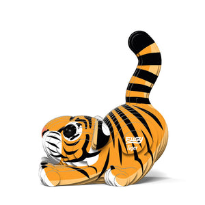 Side view image of Eugy Tiger, showing tiger model made form layers of cardboard in orange, black and white. Models paws are stretched out in front with bottom in the air and tail sticking up. White background.