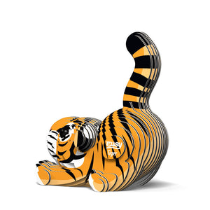 Side to rear view image of Eugy Tiger, showing tiger model made form layers of cardboard in orange, black and white. Models paws are stretched out in front with bottom in the air and tail sticking up. White background.