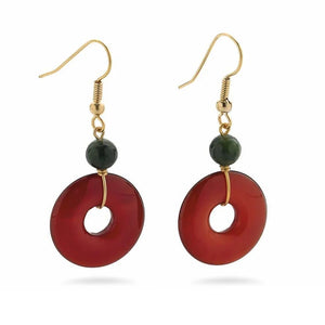 Image of gold pendant earrings with green bead and red bi disc on white background.