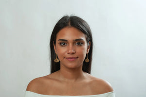 Image of girl with dark hair wearing ginkgo leaf shaped drop earrings in gold finish on white background.