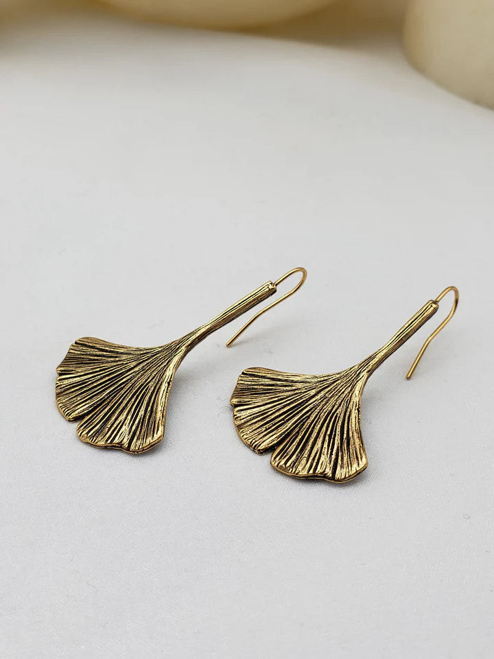 Image of ginkgo leaf shaped drop earrings in gold finish on white background.