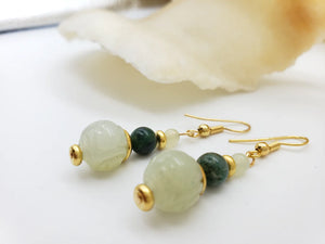 Image of pair of gold hanging earrings with three jade beads on white background.
