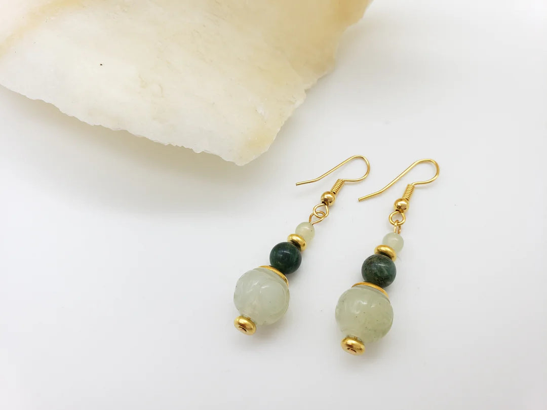 Image of pair of gold hanging earrings with three jade beads on white background.