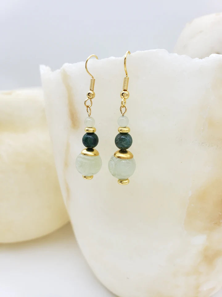 Image of pair of gold hanging earrings with three jade beads hanging on white crystal.