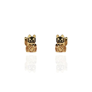 Image of a pair of polished gold stud earrings shaped like lucky cats (Maneki-neko), each with a raised paw and engraved details on the body and face. The earrings are displayed against a white background with a subtle reflection beneath them.