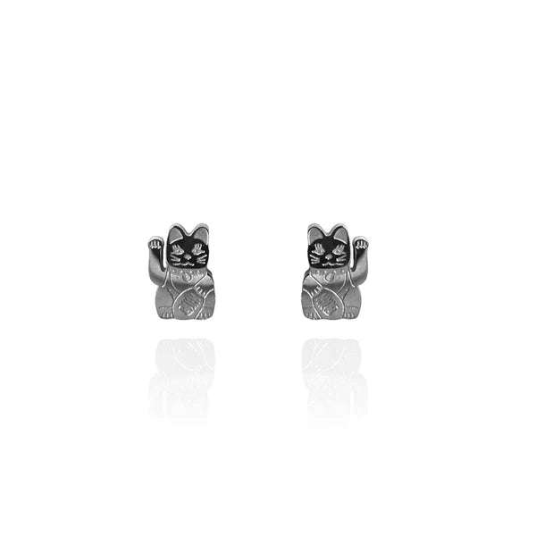 Image of a pair of polished silver stud earrings shaped like lucky cats (Maneki-neko), each with a raised paw and engraved details on the body and face. The earrings are displayed against a white background with a subtle reflection beneath them.
