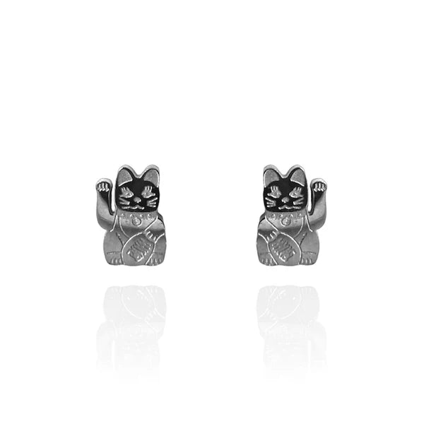 Image of a pair of polished silver stud earrings shaped like lucky cats (Maneki-neko), each with a raised paw and engraved details on the body and face. The earrings are displayed against a white background with a subtle reflection beneath them.