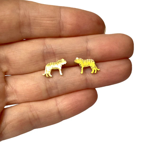 Image of a close-up of a hand holding a pair of gold-tone tiger-shaped stud earrings, showcasing their small size and engraved stripe details.