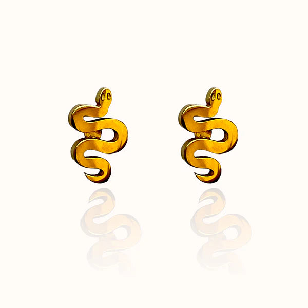 Image of a pair of gold-tone stud earrings shaped like stylized serpents with coiled bodies and small round eyes, displayed on a off white background with a subtle mirrored reflection.