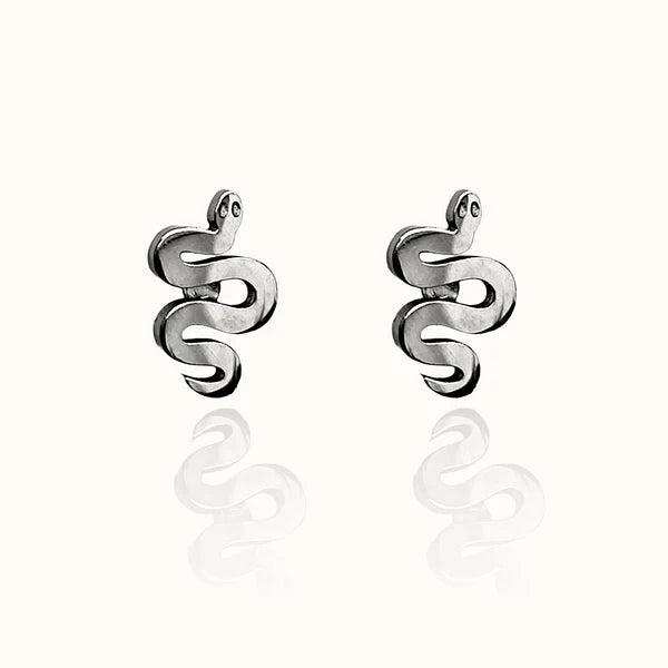 Image of a pair of silver-tone stud earrings shaped like stylized serpents with coiled bodies and small round eyes, displayed on an off white background with a subtle mirrored reflection.