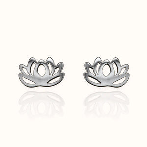 Image of a pair of polished silver stud earrings in the shape of a stylized lotus flower with open petal cutouts, displayed on am off white background with soft reflections.