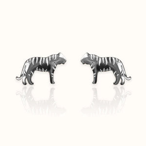 Image of a pair of silver-tone stud earrings in the shape of tigers, featuring engraved stripe details and a sleek silhouette. Displayed on an off white background.