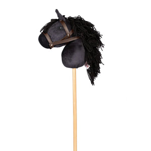 Image of black hobbie horse, showing black plush horse head with black main and brown bridle attached to a pine stock, on white background.