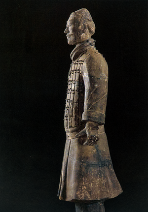 Postcard featuring a side view of a Terracotta Warrior statue in detailed armor with intricate patterns, set against a dark background.