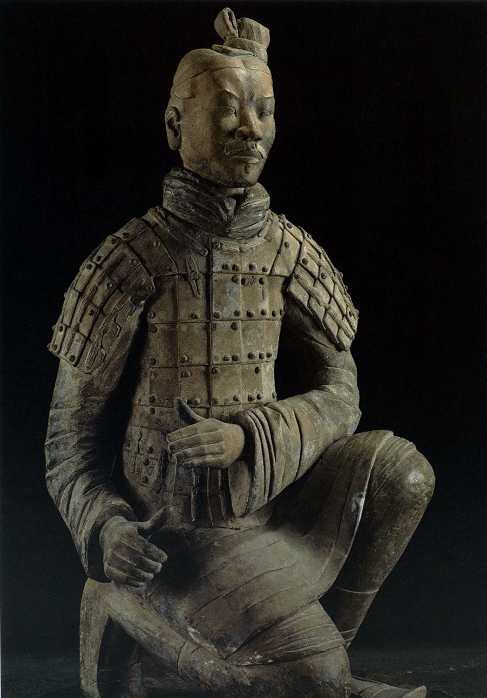 Postcard featuring a kneeling terracotta warrior statue in detailed armor with a tunic and shoulder plates, set against a dark background.