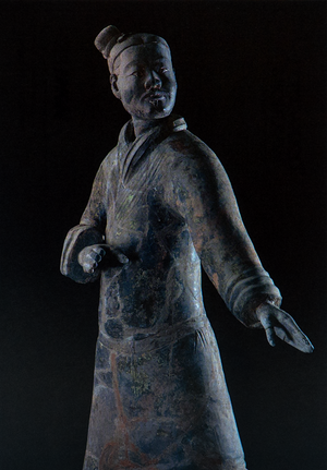 Postcard featuring a standing terracotta warrior statue in traditional armor with one arm bent and the other extended; detailed face and headpiece, set against a dark background.