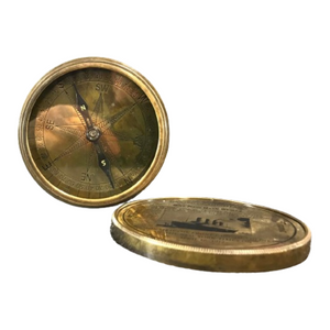 Brass compasss open showing compass face with lid nearby