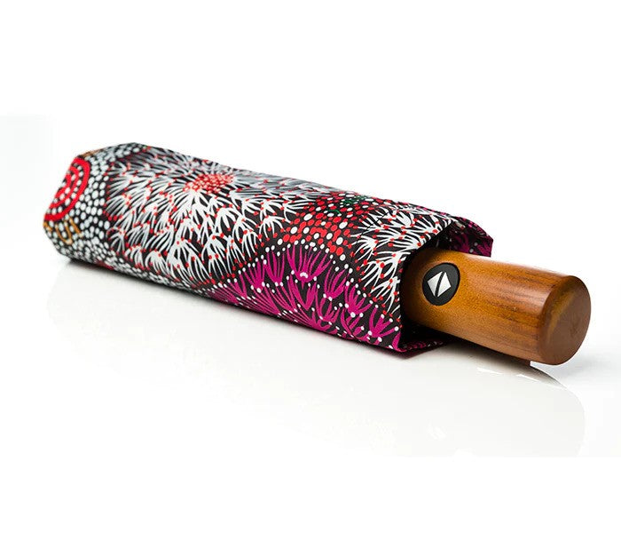 Image of folded umbrealla with floral aboriginal print by Coral Hayes and wooded handle